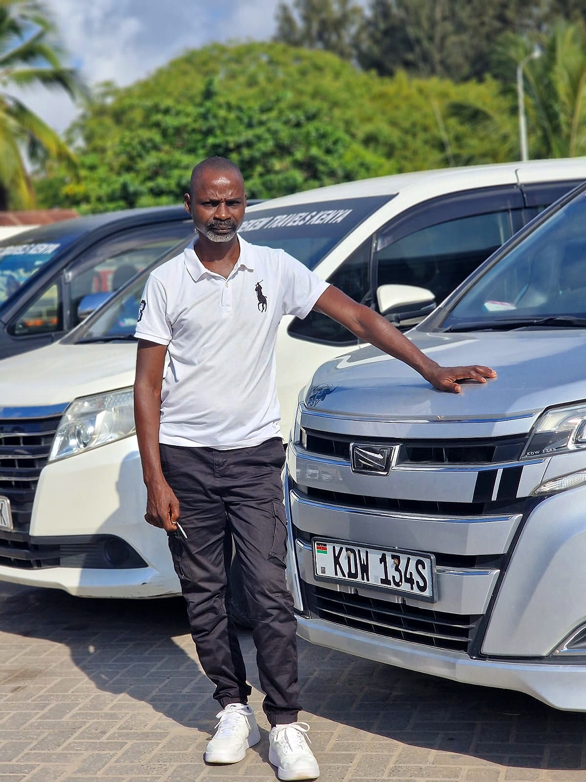 Meshidekem Travels Kenya team member standing with the company vehicle fleet